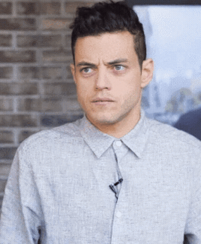 A Man In A Grey Shirt With A Microphone On His Collar GIF