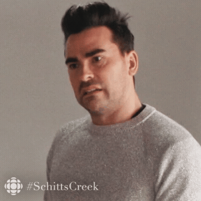 A Man In A Grey Sweater Is Looking At The Camera . GIF