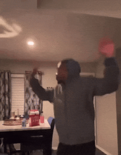 A Man In A Grey Sweatshirt Is Dancing With His Arms Outstretched GIF