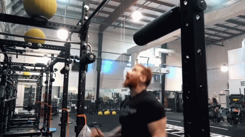 A Man In A Gym Wearing A Black Shirt That Says ' Armour ' On It GIF