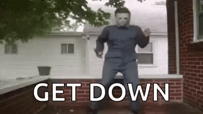 A Man In A Halloween Costume Is Dancing In Front Of A Brick House . GIF