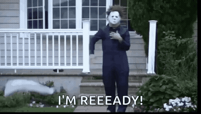 A Man In A Halloween Costume Is Standing In Front Of A House With His Hand On His Chest . GIF