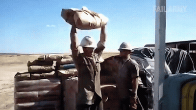 A Man In A Hard Hat Is Carrying A Bag Over His Head GIF