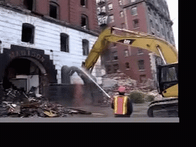 A Man In A Hard Hat Stands In Front Of A Building Being Demolished GIF