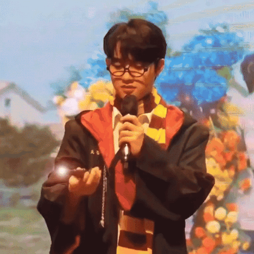 A Man In A Harry Potter Outfit Is Holding A Microphone GIF