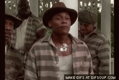 A Man In A Hat And Plaid Shirt Is Standing In Front Of A Group Of Men In Striped Shirts . GIF