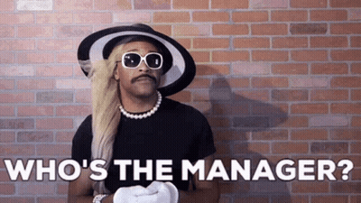 A Man In A Hat And Sunglasses Is Standing In Front Of A Brick Wall . GIF