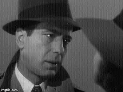 A Man In A Hat And Tie Is Looking At Another Man In A Suit . GIF