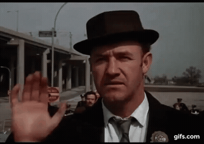 A Man In A Hat And Tie Is Waving His Hand In Front Of A Group Of People . GIF