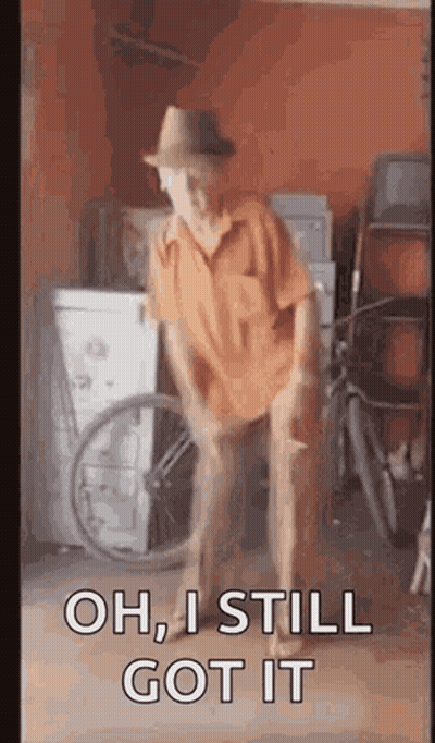 A Man In A Hat Is Dancing In A Garage With A Wheelchair . GIF