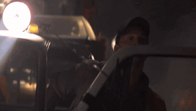 A Man In A Hat Is Driving A Car With A Light On The Top Of It GIF