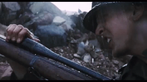 A Man In A Hat Is Holding A Gun GIF