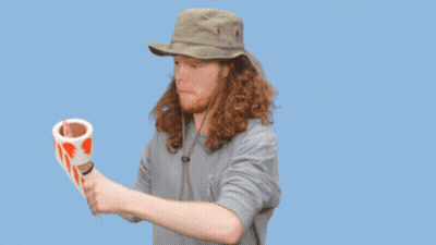 A Man In A Hat Is Holding A Roll Of Tape That Says Labels Are Stickers On It GIF