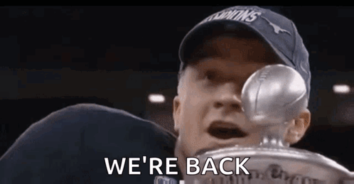 A Man In A Hat Is Holding A Trophy In His Hand . GIF