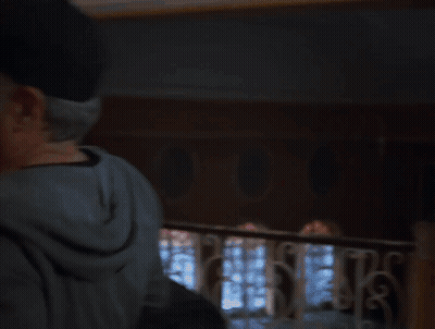 A Man In A Hat Is Hugging A Woman In A Room GIF