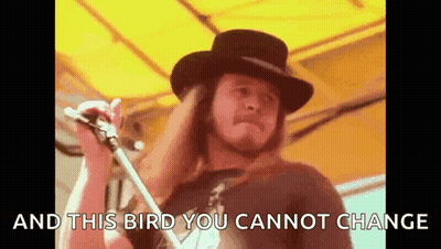 A Man In A Hat Is Singing Into A Microphone With The Words `` And This Bird You Cannot Change '' Behind Him . GIF