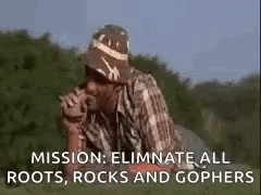 A Man In A Hat Is Smoking A Cigarette In A Field With The Words `` Mission : Eliminate All Roots GIF