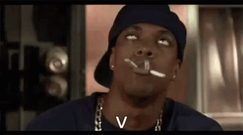 A Man In A Hat Is Smoking A Cigarette In A Room . GIF