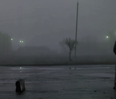 A Man In A Hat Is Standing In A Parking Lot GIF