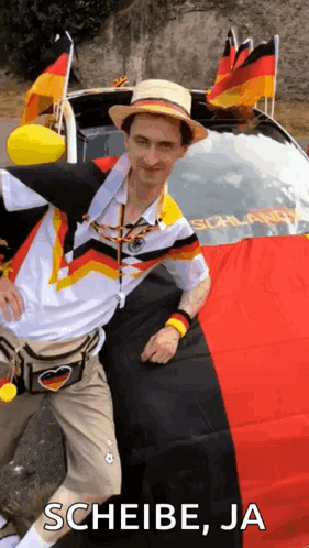 A Man In A Hat Is Standing In Front Of A Car With A German Flag On The Back . GIF