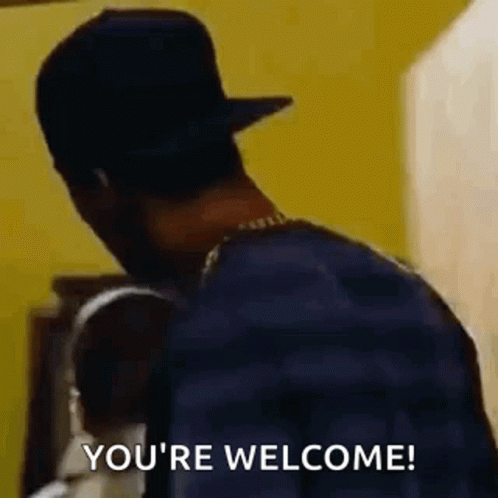A Man In A Hat Is Standing In Front Of A Yellow Wall And Saying `` You 'Re Welcome ! '' GIF