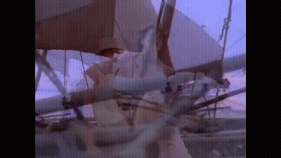 A Man In A Hat Is Standing On A Boat With A Purple Sky In The Background . GIF