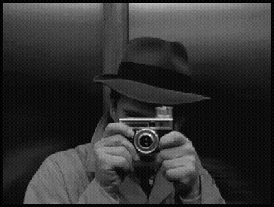 A Man In A Hat Is Taking A Picture Of Himself With A Camera GIF