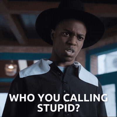 A Man In A Hat Says " Who You Calling Stupid " In Front Of A Window GIF