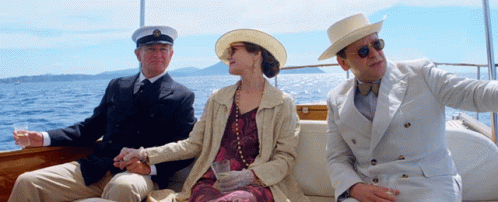 A Man In A Hat Sits Next To A Woman On A Boat GIF