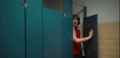 A Man In A Hat Stands In A Bathroom Stall GIF