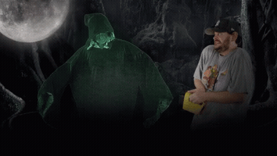 A Man In A Hat Stands In Front Of A Glowing Figure GIF