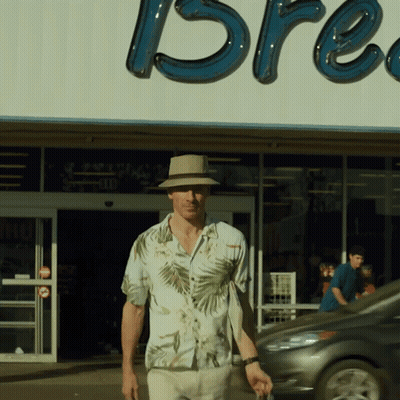 A Man In A Hat Stands In Front Of A Store That Says Bre GIF