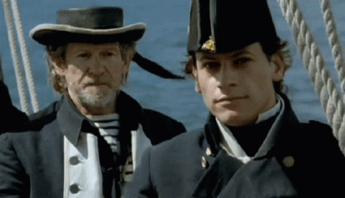 A Man In A Hat Stands Next To A Younger Man GIF