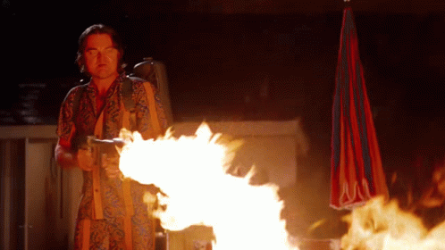 A Man In A Hawaiian Shirt Is Holding A Flamethrower In His Hand GIF