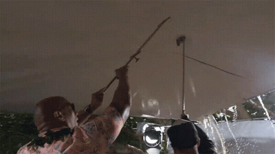 A Man In A Hawaiian Shirt Is Holding A Stick Up To A Ceiling GIF