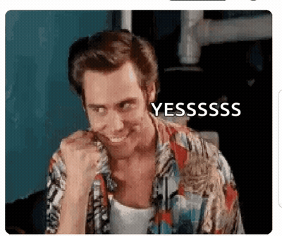 A Man In A Hawaiian Shirt Is Smiling And Making A Funny Face With His Fist In His Mouth . GIF