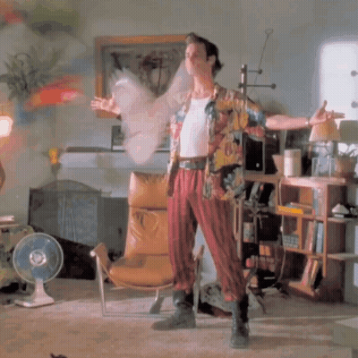 A Man In A Hawaiian Shirt Is Standing In A Room With A Fan GIF