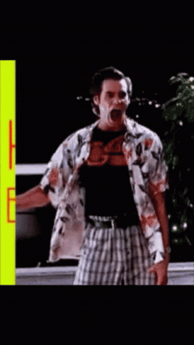 A Man In A Hawaiian Shirt Is Standing In Front Of A Yellow Sign That Says Happy Birthday GIF