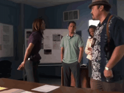 A Man In A Hawaiian Shirt Stands In A Room With Other People GIF