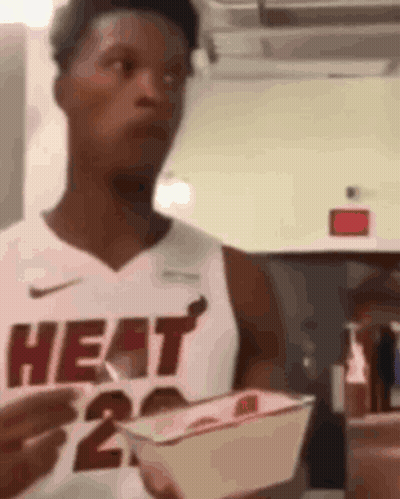 A Man In A Heat Jersey Is Holding A Basket Of Food . GIF