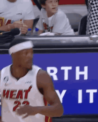 A Man In A Heat Jersey Is Standing In Front Of A Sign That Says Worth It . GIF