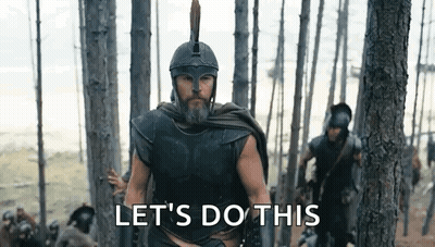 A Man In A Helmet And Armor Is Walking Through A Forest With A Group Of Soldiers . GIF