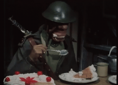 A Man In A Helmet Is Eating A Piece Of Cake With Whipped Cream GIF
