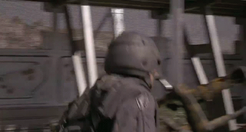 A Man In A Helmet Is Holding A Hammer In A Room With A Blurred Background . GIF