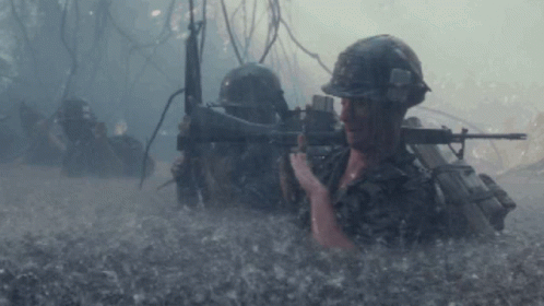 A Man In A Helmet Is Holding A Rifle In The Water GIF