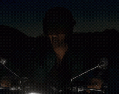 A Man In A Helmet Is Riding A Motorcycle In The Dark GIF