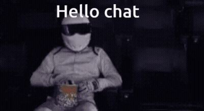 A Man In A Helmet Is Sitting In A Chair Eating Popcorn And Talking On A Cell Phone . GIF