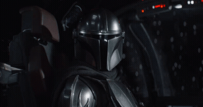 A Man In A Helmet Is Sitting In A Dark Room And Says Grogu GIF