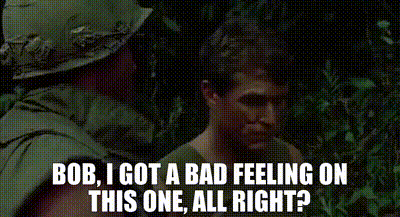A Man In A Helmet Is Talking To Another Man In The Woods . GIF