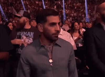 A Man In A Herman Shirt Stands In A Crowd Of People GIF